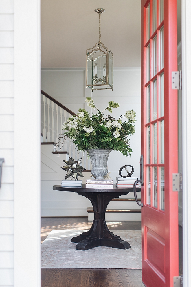 Classic foyer with round table, neutral rug and grid board and batten wainscoting painted in Benjamin Moore Decorator White #foyer #gridboardandbetten #wainscoting #BenjaminMooreDecoratorWhite