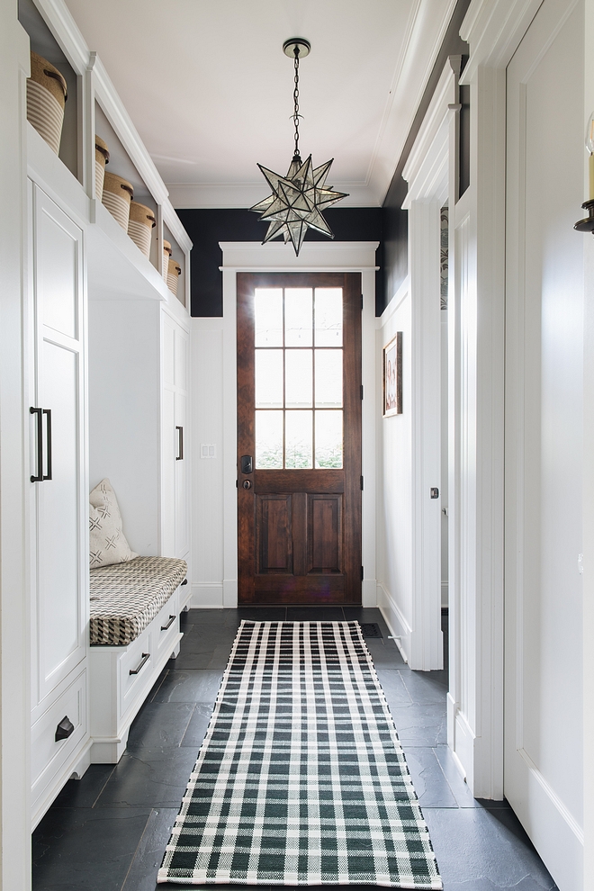 Mudroom with wainscoting, black walls painted in Benjamin Moore Black and built-ins painted in Benjamin Moore Decorators White Flooring is Black Slate Tile and lighting is Moravian Star pendant #mudroom #wainscoting #Benjaminmoore