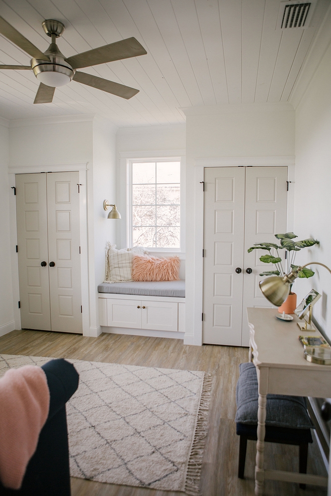 Closets, with greige doors, flank a window-seat