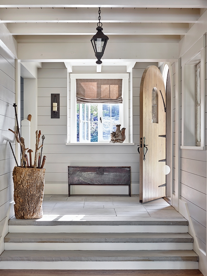 Foyer An enchanting arched door opens to an equally enchanting foyer with natural stone flooring and nickel joint walls shilap #foyer #shiplap #archeddoor #naturalstoneflooring #nickeljointwall #nickeljointshiplap #nickeljointpaneling #nickeljoint