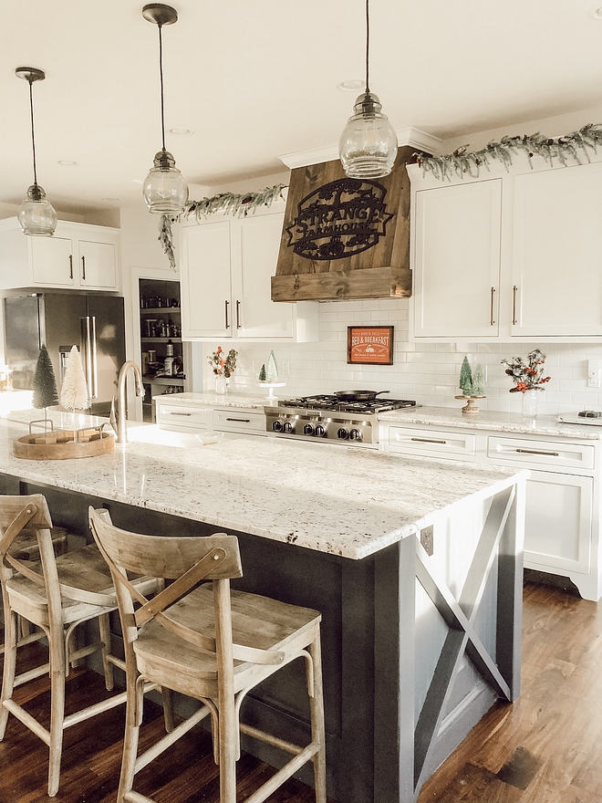 A stained wooden hood and a kitchen island with X insets give a farmhouse feel to this large kitchen #farmhousekitchen #farmhouse #kitchen