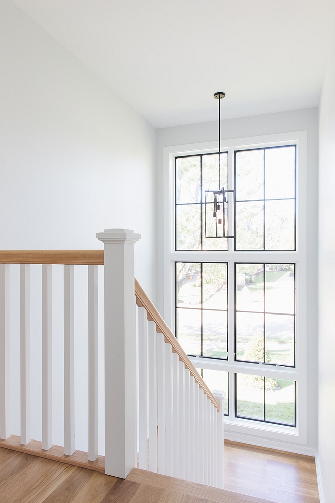 Floor-to-ceiling windows bring plenty of natural light to this stairway Wall paint color is Sherwin Williams Site White #stairway #windows #paintcolor