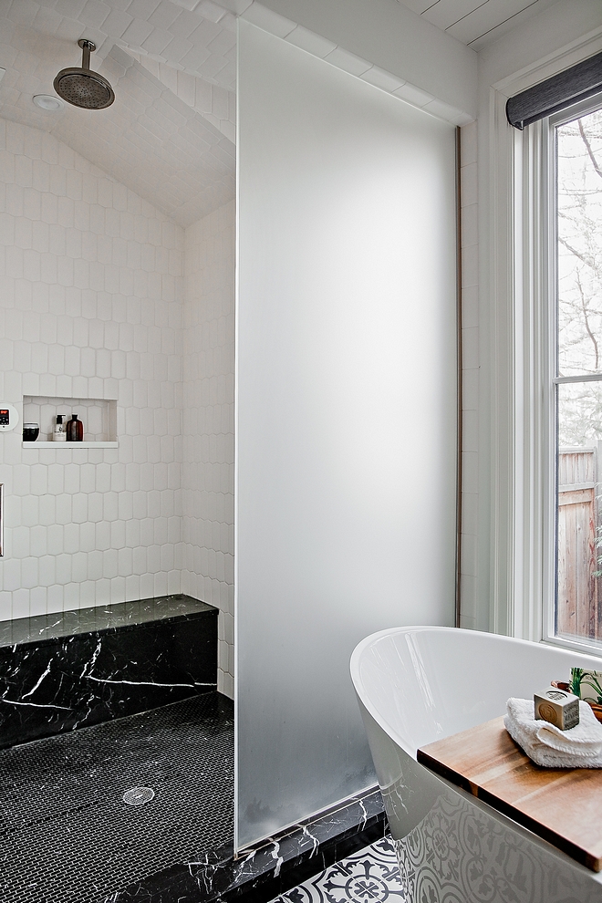 The shower features frosted glass doors and Nero Marquina marble accents #shower #frostedglassshower