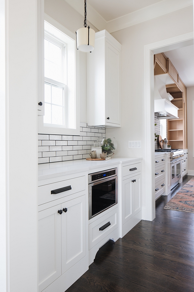 A bright white butler's pantry is located between the dining room and kitchen Cabinet paint color is Benjamin Moore Simply White Walls are Benjamin Moore Classic Gray with trim also in Benjamin Moore Simply White Save this perfect color scheme for future references #colorscheme #cabinetpaintcolor #wallpaintcolor #trimpaintcolor #paintcolor