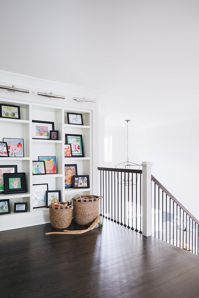 This large landing area features custom-stained solid Oak hardwood floors, custom staircase with metal spindles and a asymmetrical bookcase #solidOakfloors #hardwoodfloors #hardwoodflooring #staircase #metalspindles #asymmetricalbookcase