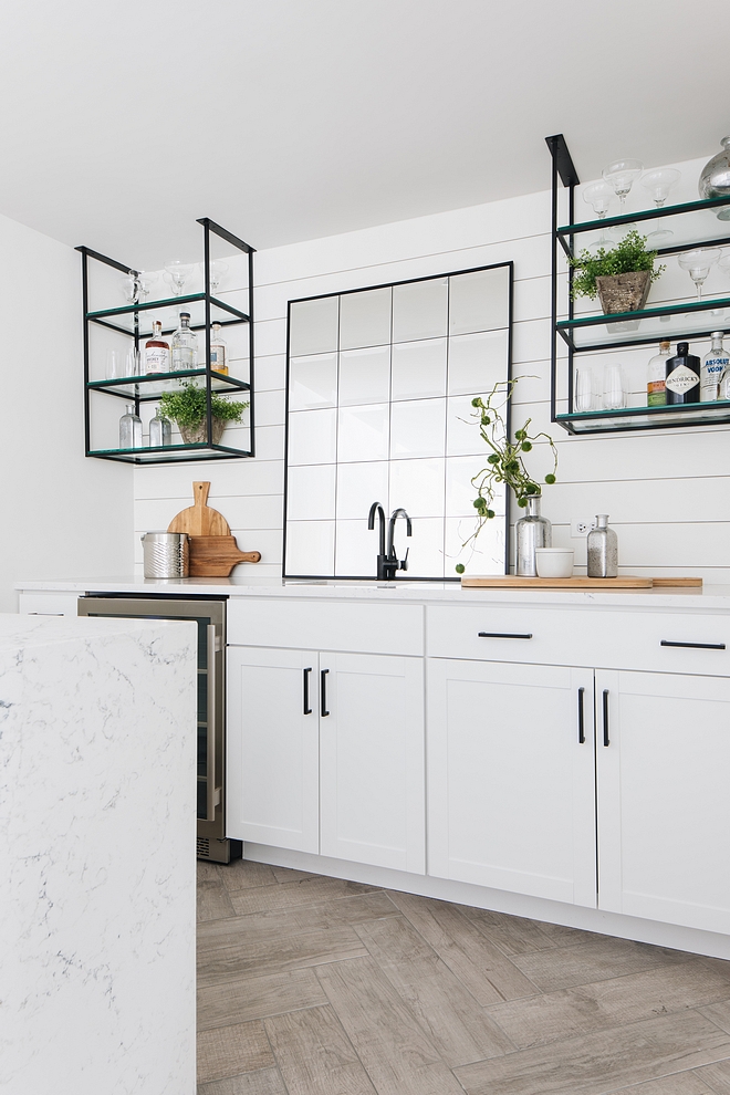 White basement bar painted in Benjamin Moore Simply White features white marble quartz countertop, shilplap backsplash and custom metal and glass wall shelves #basement #bar #shilpap #shiplapbacksplash #metalshelves