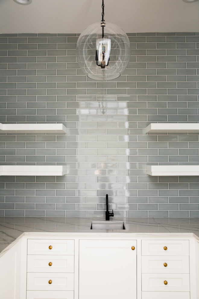 Pantry features a grey subway tile backsplash, white cabinets, brass knobs and floating shelvess #Butlerspantry #pantry #greysubwaytile