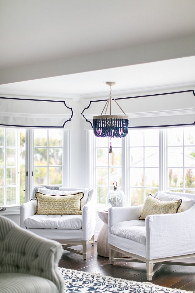 Bedroom sitting area with relaxed white linen chairs and navy agate bead chandelier and white Roman Shades with blue trim #sittingarea #bedroom #chairs #beadchandelier #Romanshades