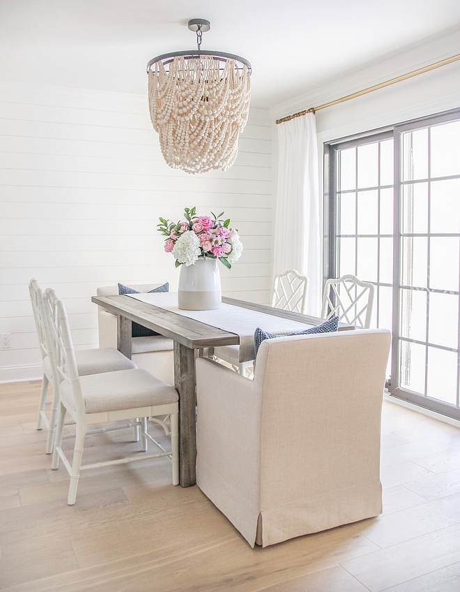 Neutral White Dining Room with White Shiplap Accent Wall, Cream beaded chandelier, Natural wood dining table, linen dining chairs and white Chippendale dining chairs #DiningRoom #Neutraldiningroom #WhiteDiningRoom #Shiplap #beadedchandelier #diningtable #linendiningchair #whiteChippendalediningchair