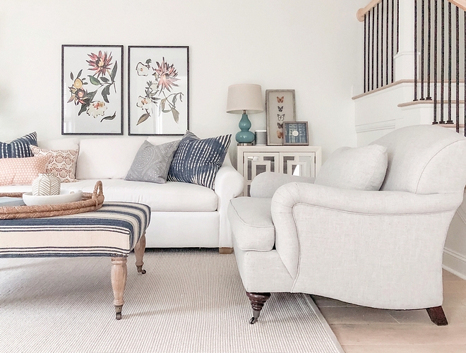 Neutral Living Room White Linen Sofa with Natural Linen Accent Chair and neutral rug Pillows, framed artwork and an upholstered ottoman brings color to this neutral living room #NeutralLivingRoom #WhiteLinenSofa #NaturalLinen #AccentChair #neutralrug #Pillows #framedartwork #ottoman