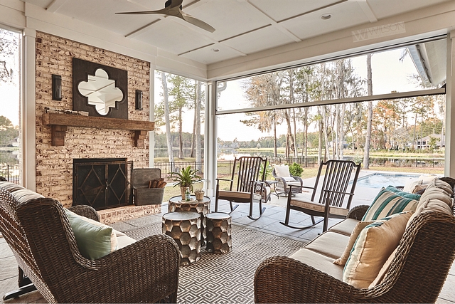 Bi-fold patio doors open to a beautiful screened porch with brick fireplace and coffered ceiling #Bifoldpatiodoor #screenedporch #brickfireplace #cofferedceiling