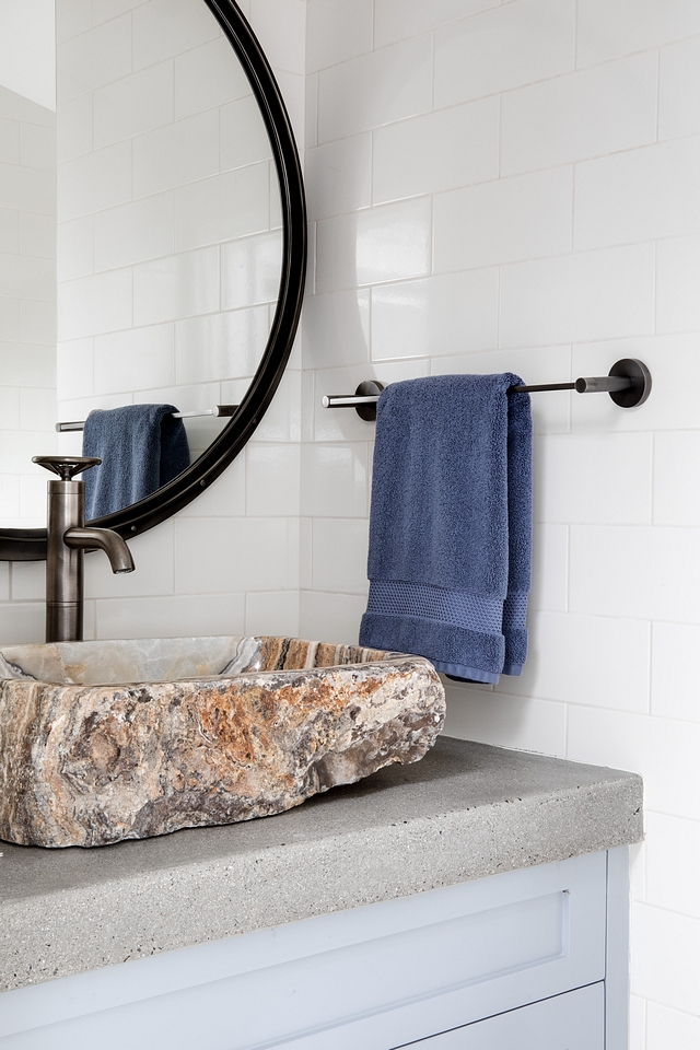 Bathroom features and hand carved stone sink, concrete countertops and floor to ceiling beige subway tiles on all walls #bathroom