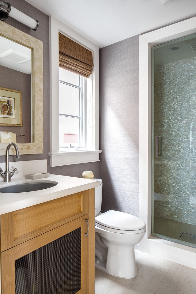 Bathroom Walls are wallpapered in a mauve grasscloth Limestone countertop and floor with mosaic mother of pearl on shower walls Cabinet is Shaker style in rift white oak with clear finish and wire mesh insert #bathroom #wallpaper #motherofpearltile