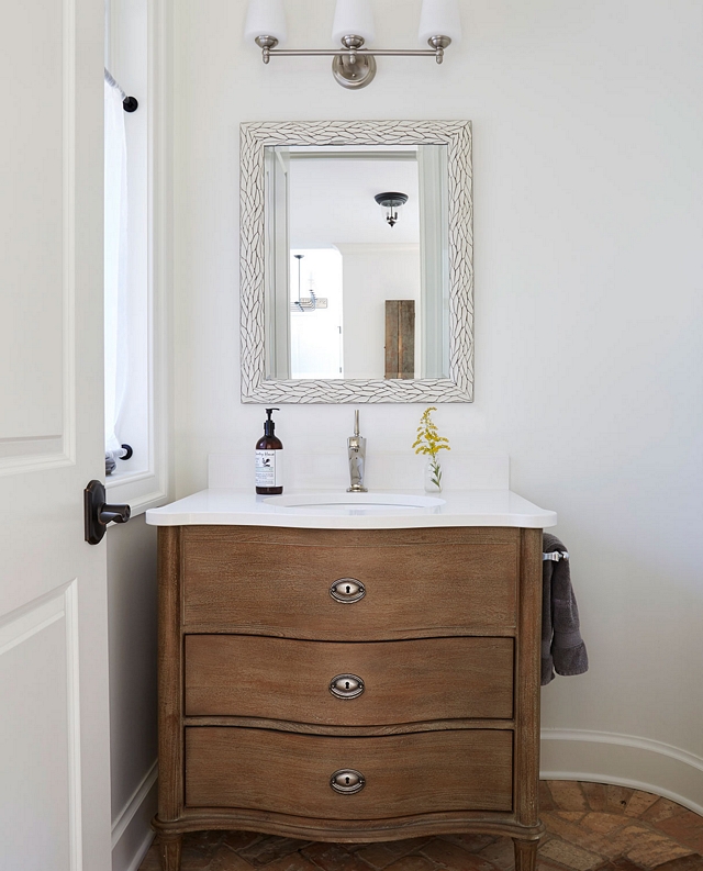 Powder room features a Restoration Hardware vanity and brick flooring