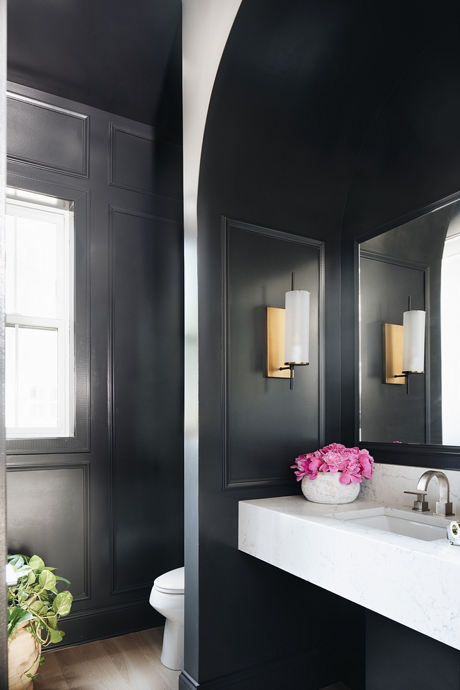 This powder room features black paneled walls, painted in Benjamin Moore Wrought Iron 2124-10, and a marble-looking floating vanity