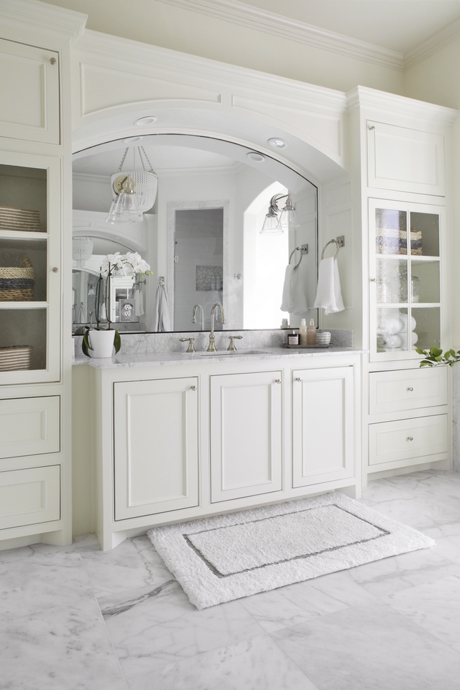 Bathroom cabinets feature a warm white color, Benjamin Moore Swiss Coffee, and doors with seeded glass