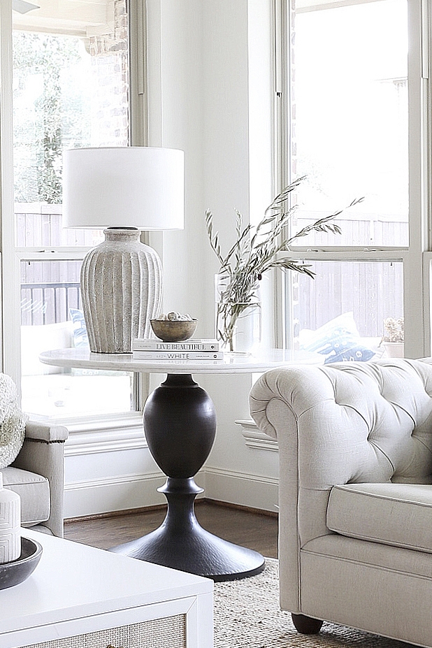 A marble pedestal round table is accentuated with a large Terracotta table lamp and neutral decorative elements