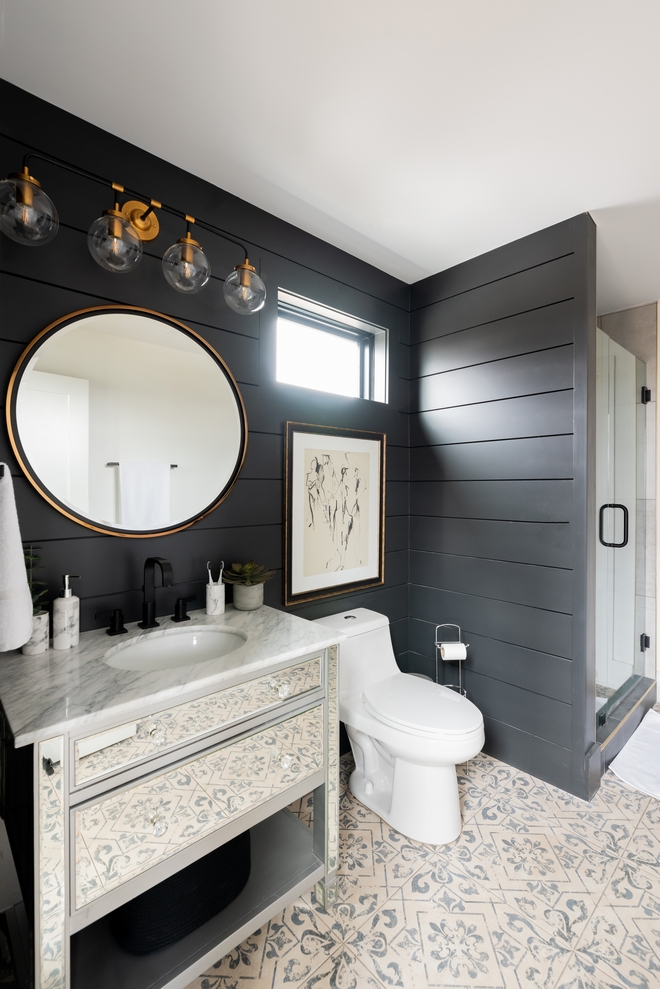 The beautiful and sophisticated Main Bathroom features black Shiplap walls, a mirrored vanity and patterned floor tiles