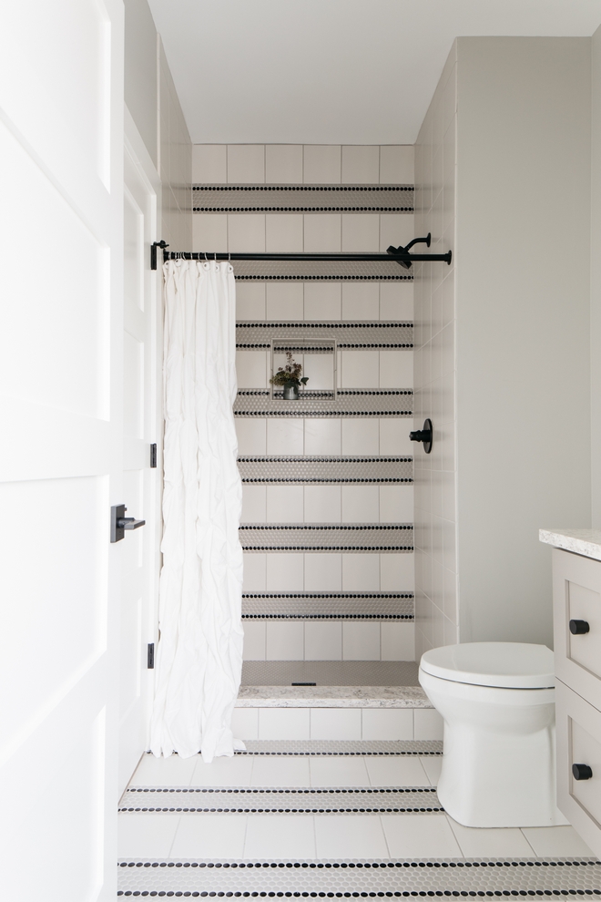 You really don't need to break the bank when designing a child's bathroom and this one is here to show us how it's done. Combine affordable yet timeless tiles and be creative with the design to make the entire room pop and feel authentic Bathroom Tiling: Matte Grey Penny Tile (also applied to the shower pan), Black Matte Penny Tile, 8x8 White Tile