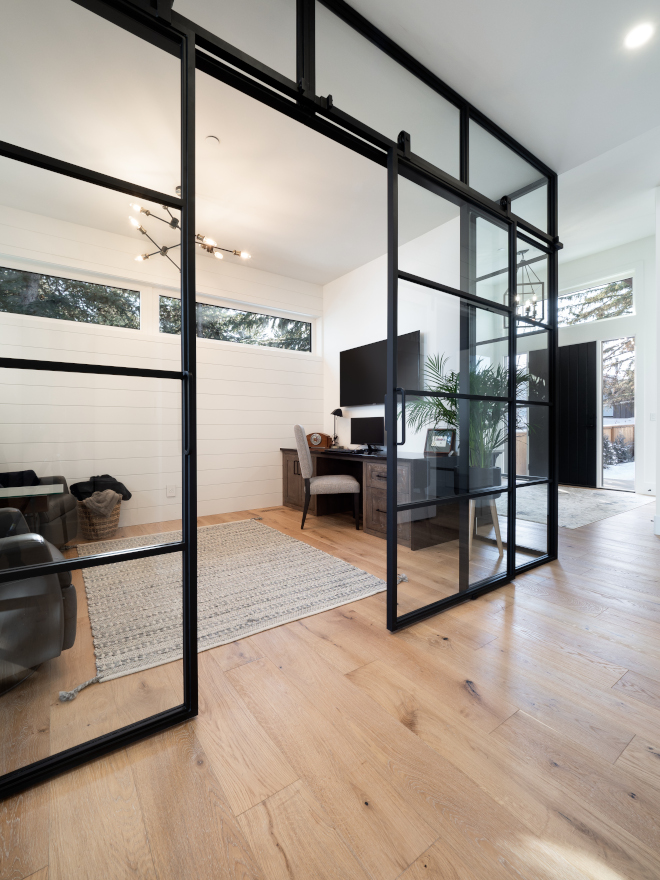 Black iron framed glass encloses the den with sliding double doors and clerestory windows bringing light and views of the treetops without compromising privacy Den #Blackironframedglassencloses #den #slidingdoubledoors #clerestorywindows