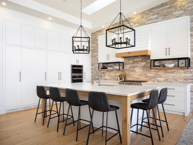 Kitchen Marble stone accents the kitchen wall and is contrasted by simple slab cabinetry with details such as metal open shelves shiplap hood range #Kitchen #Marblestonewall #stoneaccentwall #kitchenwall #slabcabinetry #metalopenshelves #shiplaphood #shiplaphoodrange