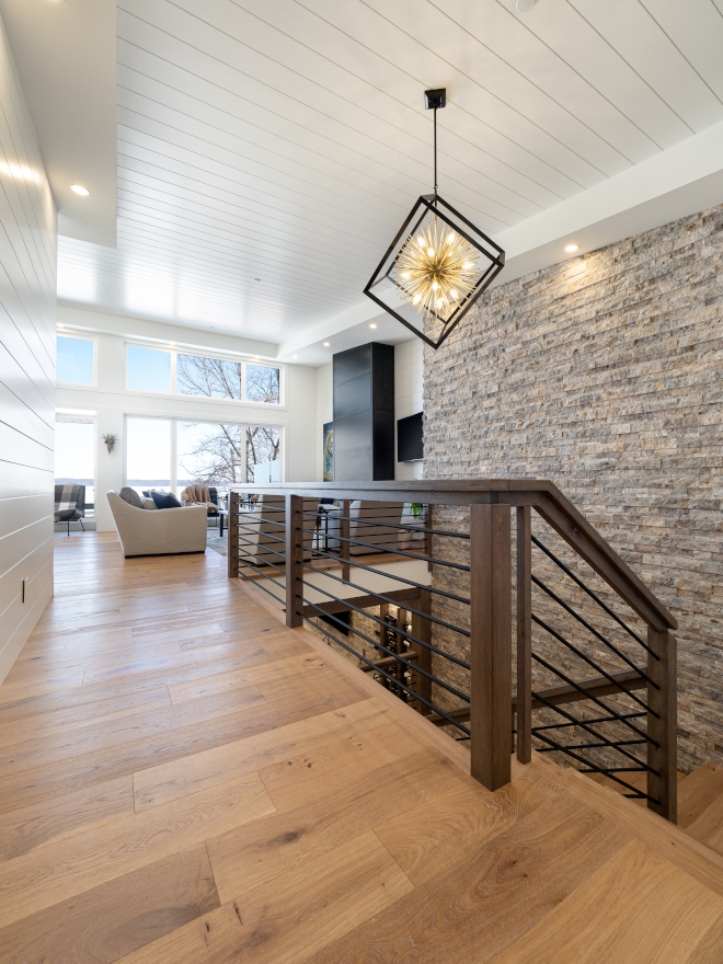 The open stairwell hosts a split Travertine feature wall and unique horizontal steel and wood railing Modern Staicase Modern Home Staircase Modern Farmhouse Staircase #openstairwell #Travertine #horizontalsteel #woodrailing #ModernStaicase #ModernHome #Staircase #ModernFarmhouse #ModernStaircase