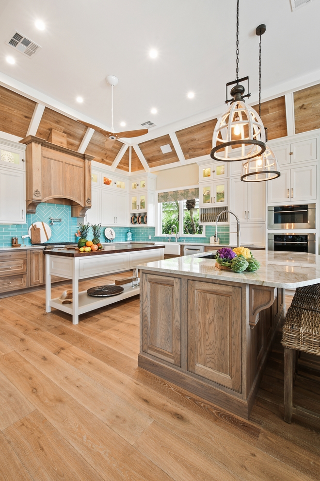 The kitchen features white inset upper cabinetry balanced with rustic Hickory base cabinets with a driftwood feel. The driftwood V-groove ceiling is framed in white beams and the two islands offer a great work space as well as an island for socializing