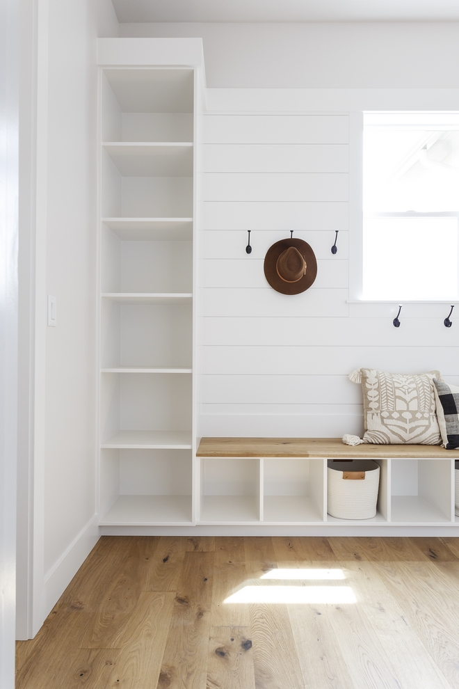 The mudroom bench features hardwood top. Shiplap paneling accentuates the mudroom back wall. Cabinetry and shiplap are in Sherwin Williams Snowbound