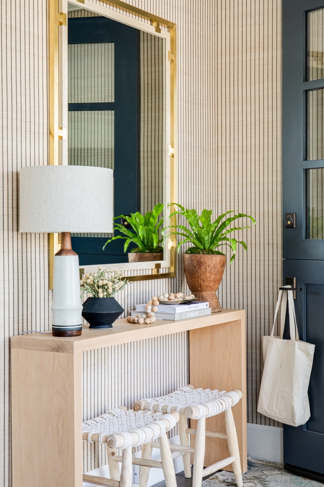 Waterfall Console Table Foyer featuring a light wood waterfall console table a top with a brushed brass frame mirror and a pair of rope and wood frame accent stools #WaterfallConsoleTable #consoletable #Foyer #lightwood #waterfallconsoletable #brushedbrassmirror #ropeandwoodstool #woodaccentstool #accentstools