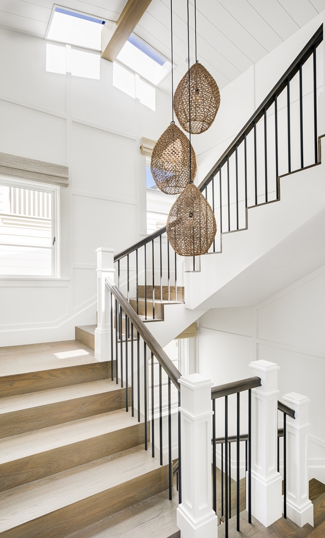 Staircase Stairs Waterfall staircase tread staircase features rope pendants hung in different heights and waterfall-style White Oak tread Walls are clad in full-height simple shaker paneling in Dunn-Edwards Whisper White #Staircase #Stairs #Waterfallstaircasethread #staircasetread #ropependant #WhiteOak #tread #shakerpaneling