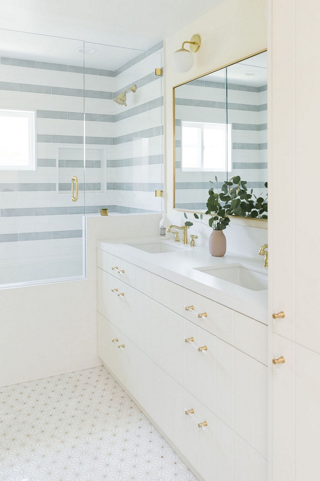 Vertical plank cabinetry and striped shower tiles add plenty of interest to this newly-renovated bathroom #Verticalplankcabinetry #plankcabinetry #stripedshower #showertile #bathroom