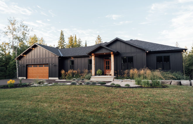 Black Modern Farmhouse with Timber We decided to pair the moody colour with black windows with a simple vertical grill down the centre on a single hung window giving it a modern farmhouse feel To give the front of the home a bit of character and interest we chose to have large pine timbers flanking our medium oak fibreglass front door and a steel garage door with a wood grain to balance it off yet add contrast against the dark siding color Black Modern Farmhouse with Timber #BlackModernFarmhouse #Timber