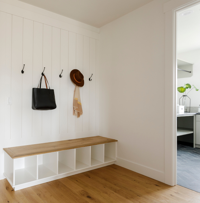 Mudroom bench with hardwood top and Vertical Shiplap wainscot above Mudroom features vertical shiplap behind bench in Sherwin Williams Snowbound Bench seat is made out of hardwood floor planks #Mudroom #bench #hardwood #VerticalShiplap #wainscot #shiplap #mudroombench #SherwinWilliamsSnowbound #hardwoodfloor #planks