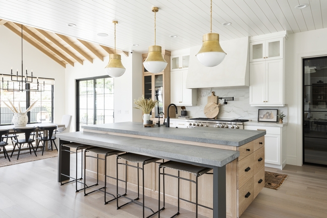 Featuring a combination of white cabinets and White Oak this kitchen exudes personality and intriguing elements that are far from being boring On the right a custom metal and glass door conceals the walk-in pantry #whitecabinet #WhiteOak #kitchen #elements #metalandglassdoor #walkinpantry #pantry