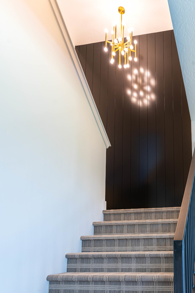 The main staircase features plaid carpeting flooring and black vertical shiplap in Sherwin Williams Caviar #staircase #plaidcarpeting #flooring #blackverticalshiplap #blackshiplap #SherwinWilliamsCaviar