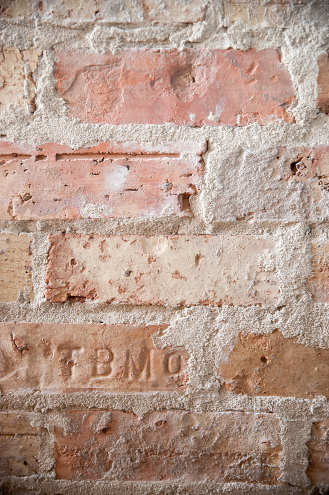 The fireplace surround is faced with antique Chicago brick visibly detailed with letterings and aged imperfections