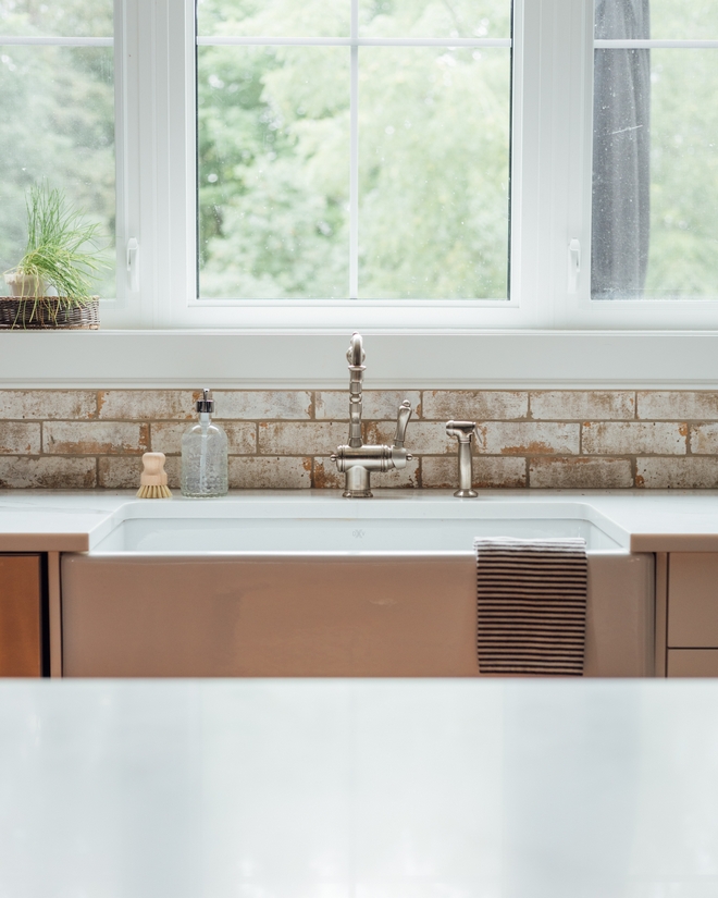 Kitchen with distressed brick tile backsplash and farmhouse sink