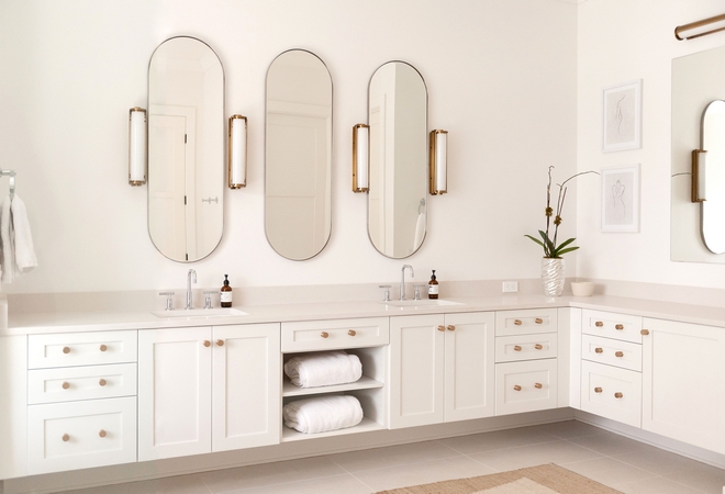 An all-white master bathroom with accents of brushed gold in the hardware and light fixtures wrapped around concrete quartz countertops and white rectified tile for flooring makes this high traffic space warm and inviting
