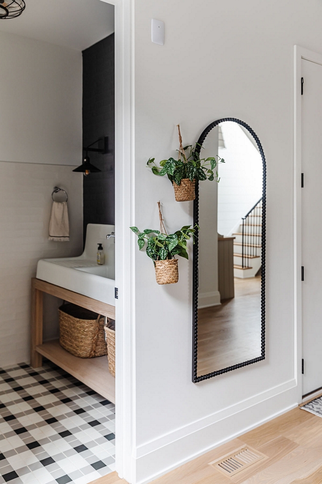 A powder room sitting adjacent to the mudroom has a more casual feel with a cast-iron sink and plaid tile floor perfect for kids stopping in before or after school #powderroom #powderbath #bathroom #mudroom