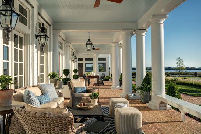 Waterfront covered porch with built-in benches nestled between columns and light blue nickel ceilings #backporch #porch #waterfront #bluceiling #porchblueceiling