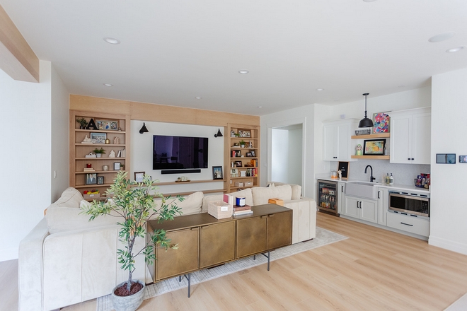 A custom White Oak entertainment center adds warmth and storage to this space while a Kitchenette is the perfect spot to prepare snacks