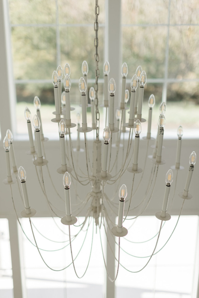 An ornate yet dainty chandelier adds a little drama to this two-story Living Room #chandelier #twostoryceiling #livingroom