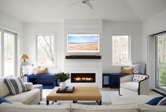 On each side of the fireplace we created custom built-in benches for the family dog allowing the pup to sit on top of the benches and look out the windows Side cabinets on the benches which are painted in Benjamin Moore Symphony Blue were added for extra storage