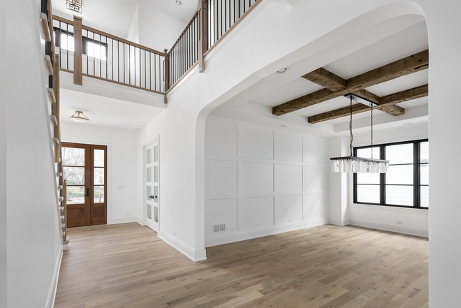 Dining Room features a large arched doorway and grid board and batten accent wall Ceiling beams are reclaimed beams from a Barn in Ohio #diningroom