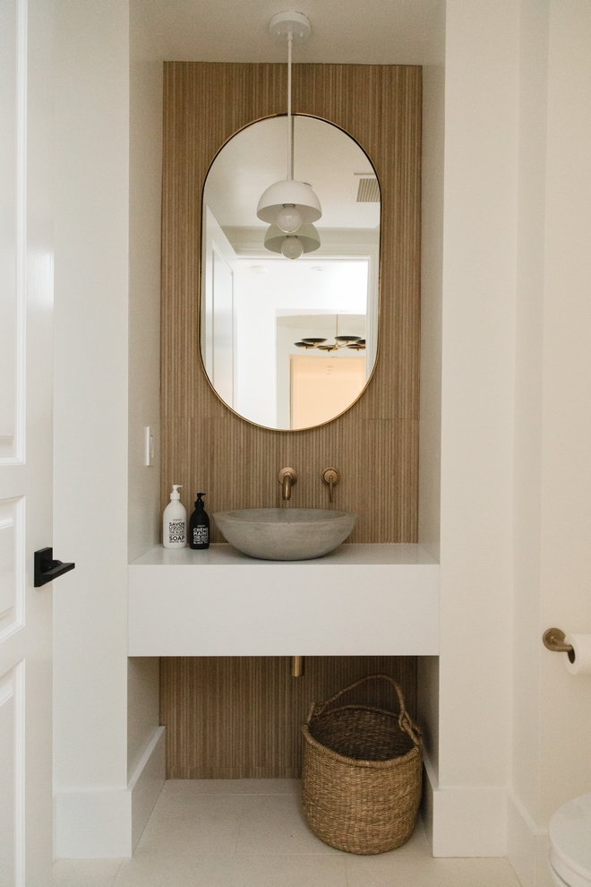 Powder Room features a custom floating vanity tucked into a nook clad with slat wood-looking tile #PowderRoom #floatingvanity #nook #slatwood #woodtile