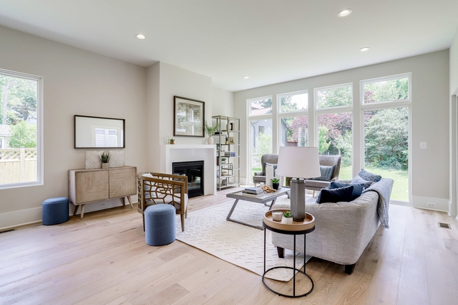 The blue and pebble gray furnishings further the coastal theme within the home The wood accent chair next to the fireplace evokes a natural, whimsical character which softens the clean rigid lines within the rest of the room #livingroom #colorscheme #woodchair #accentchair