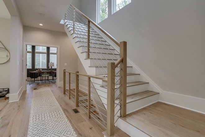 Keeping the mood light and airy the builder chose to paint the stair riders white The use of the nickel metal horizontal railing compliments the use of nickel and chrome finishes throughout the house and doesn’t weigh down the space #staircase #stair #horizontalrailing