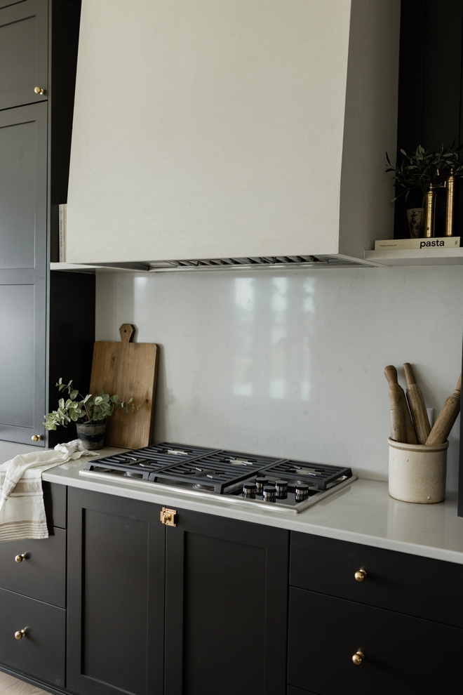 Black kitchen with Kitchen Slab Countertop and white stucco hood vent