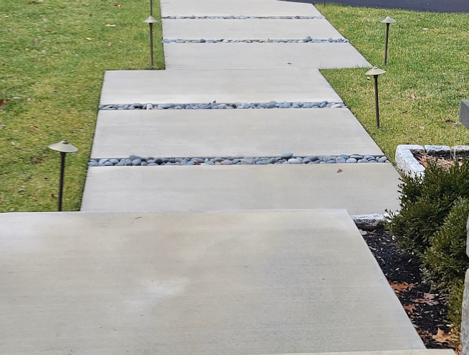 Walkway Mexican River Stone was added in a concrete trough to prevent weeds growing in between the concrete pored pavers