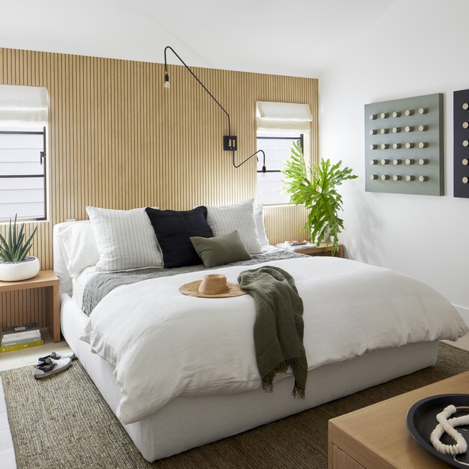 A wood slat accent wall, along with a slipcovered bed gives an organic and zen vibe to this guest bedroom Perfection #woodwall #slatwall #slatpaneling #bedroom